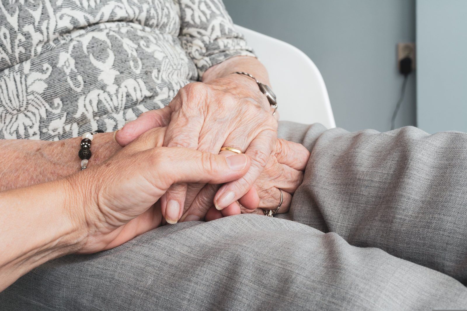 Les mains d'une personne âgée posées sur ses genoux